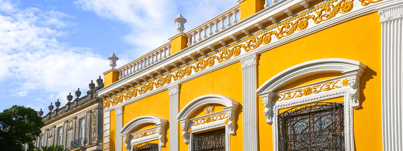 Coloridas fachadas coloniales en el centro histórico de Mérida, representando la riqueza cultural y arquitectónica de la ciudad. Explora estos vibrantes paisajes en tu próxima escapada cultural con Flex Eco Taxi.