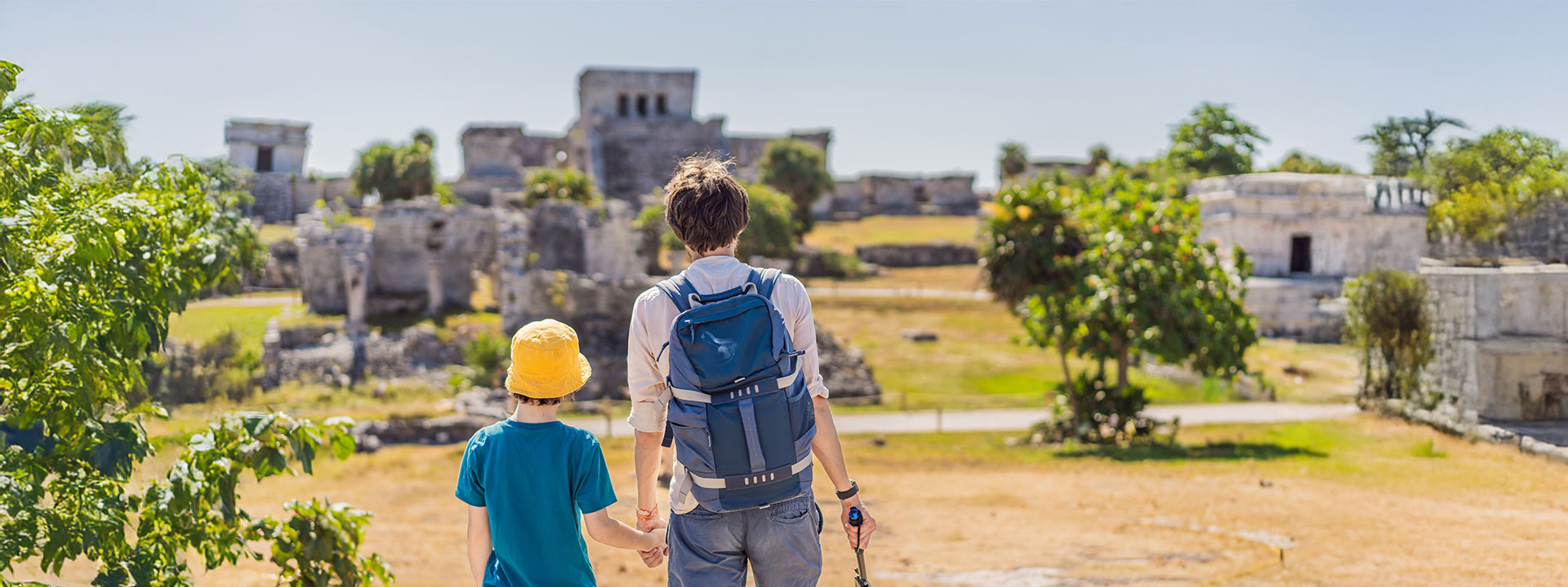 Una familia disfrutando de la impresionante vista de las ruinas de Tulum, con el mar Caribe al fondo, capturando un momento de historia y aventura.