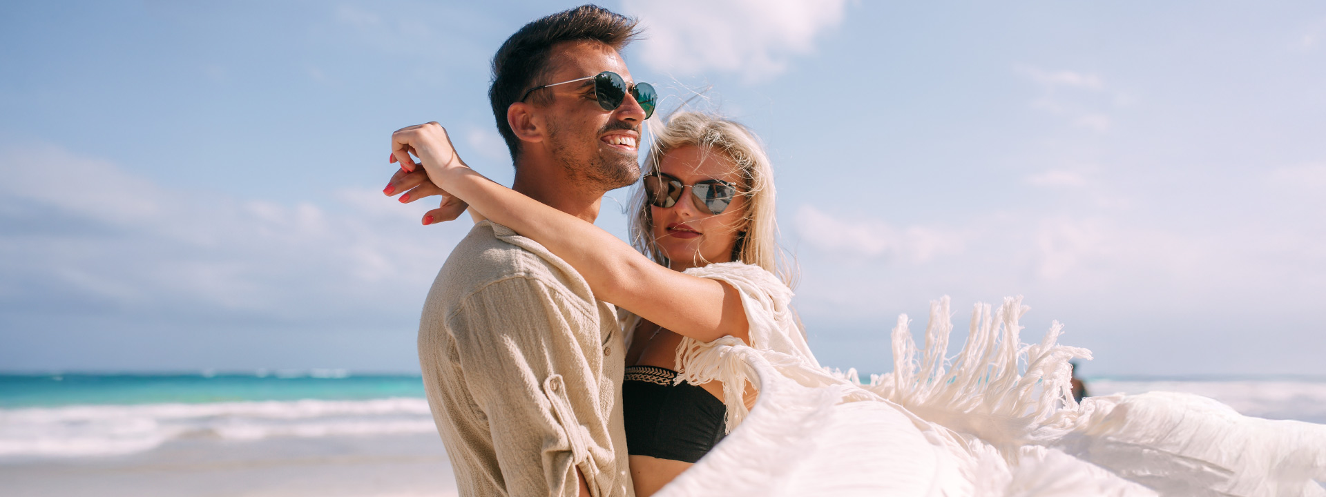 Couple relaxing on a pristine white-sand beach in Cozumel, Mexico, with turquoise waters in the background. Book your ride with Flex Eco Taxi for a smooth journey from the airport.