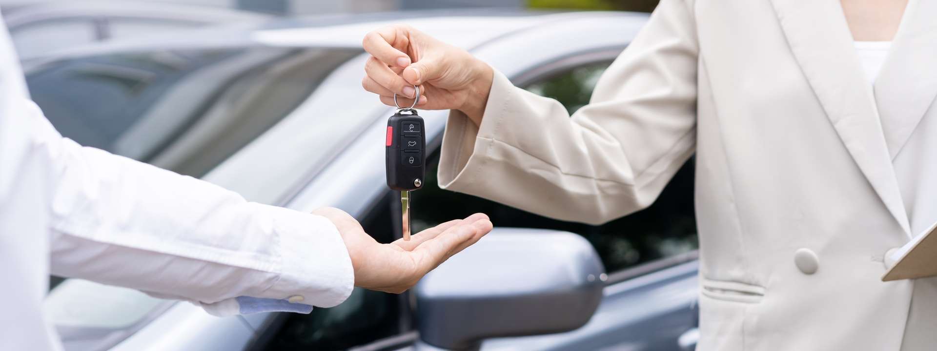 Person handing over car keys to a customer as part of a car rental service.