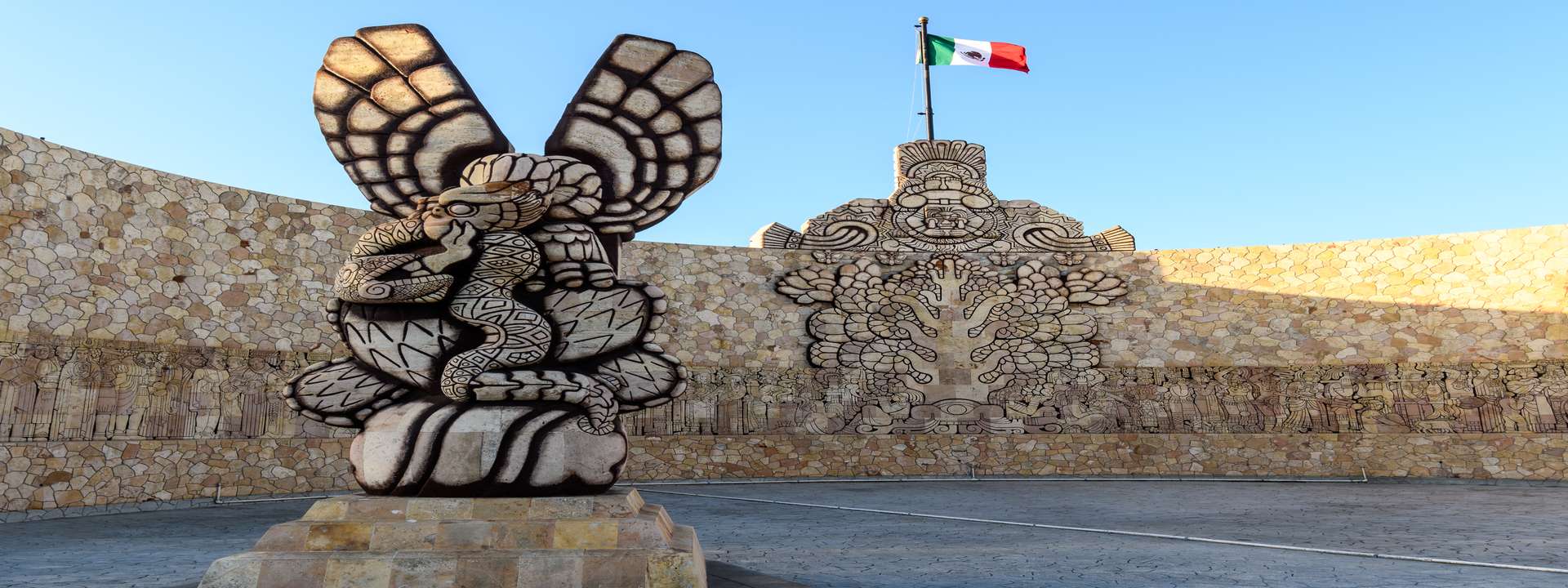 Mexican flag waving proudly in front of ancient Mayan ruins on a sunny day—a symbol of history, culture, and beauty that invites exploration.