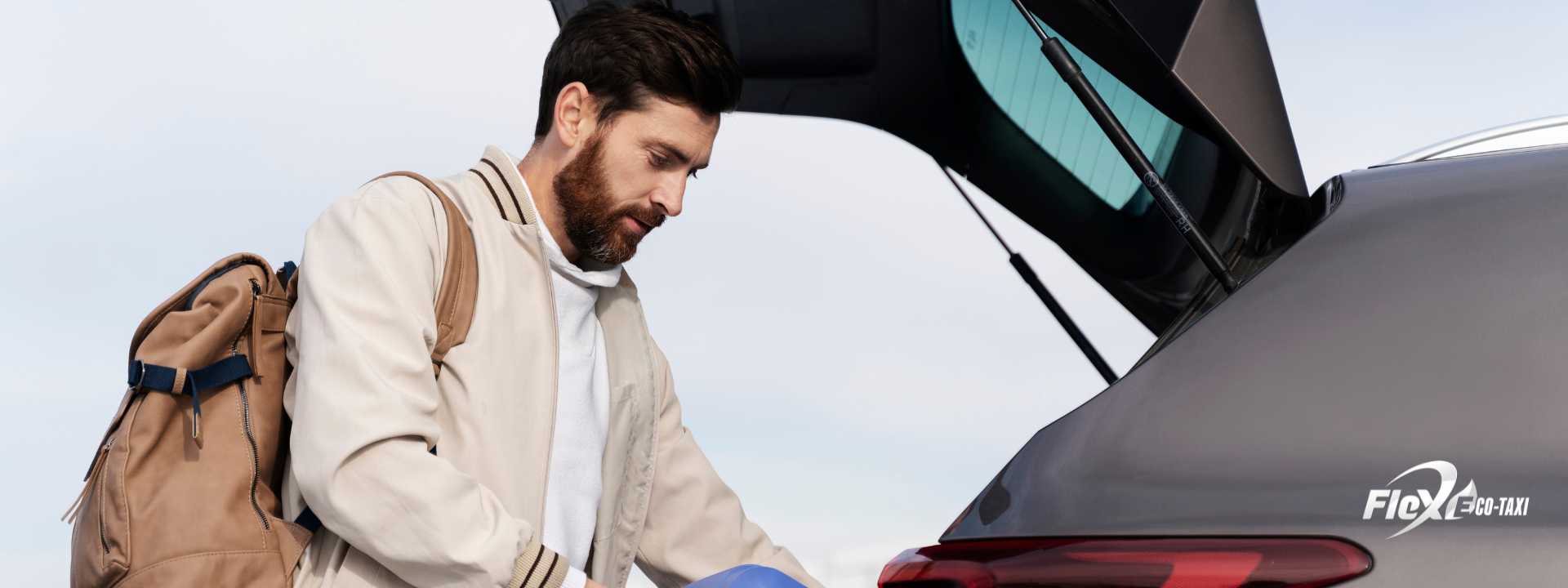 Person loading suitcases into the trunk of a car, ready to start a trip, wearing casual clothes and a relaxed expression.